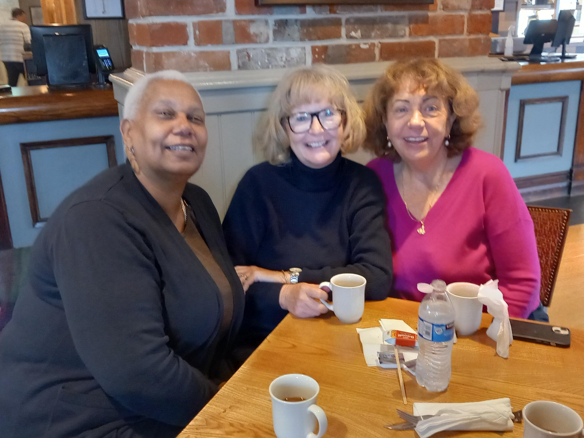 Three TACT foster carers smiling whilst enjoying a coffee