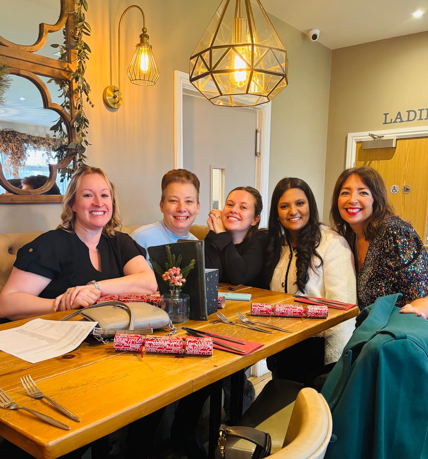 Five foster carers sat at a table smiling