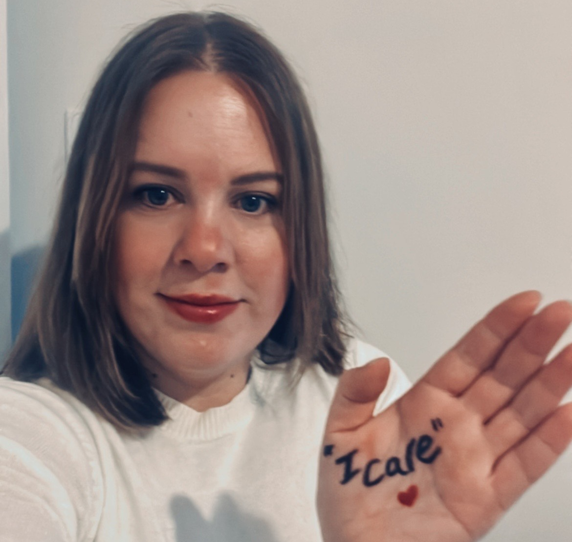 Kayleigh with I Care written on her palm, for Care Day