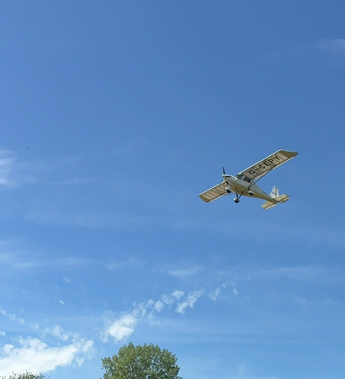 The underneath of a plane as it flies over a field
