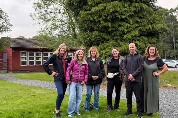 Six TACT foster carers smiling at Broomlee Outdoor Education Centre