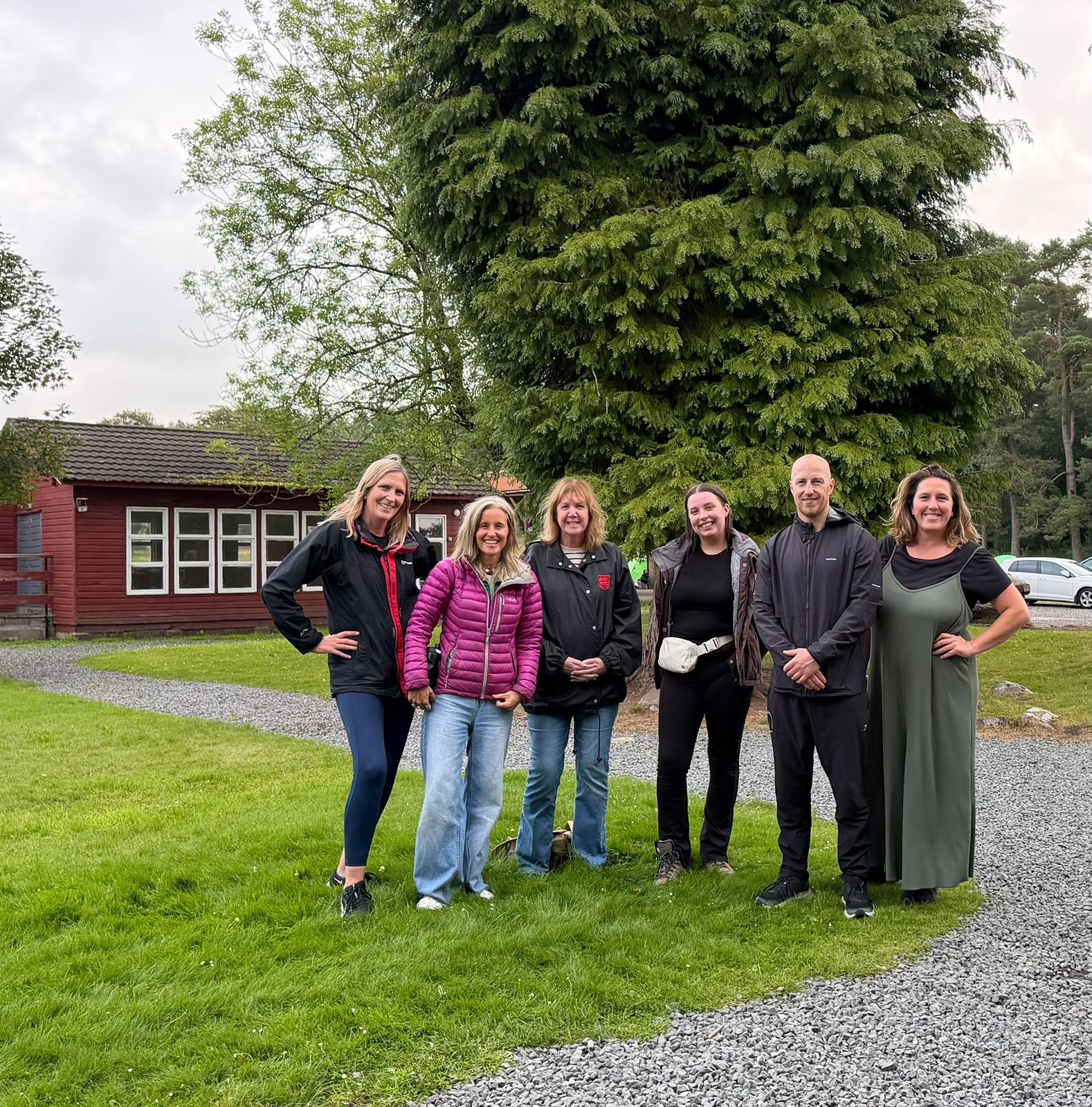 Six TACT foster carers smiling at Broomlee Outdoor Education Centre